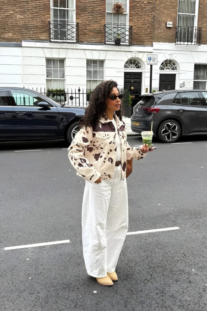 Woman in a cow-print jacket with white jeans on a city street