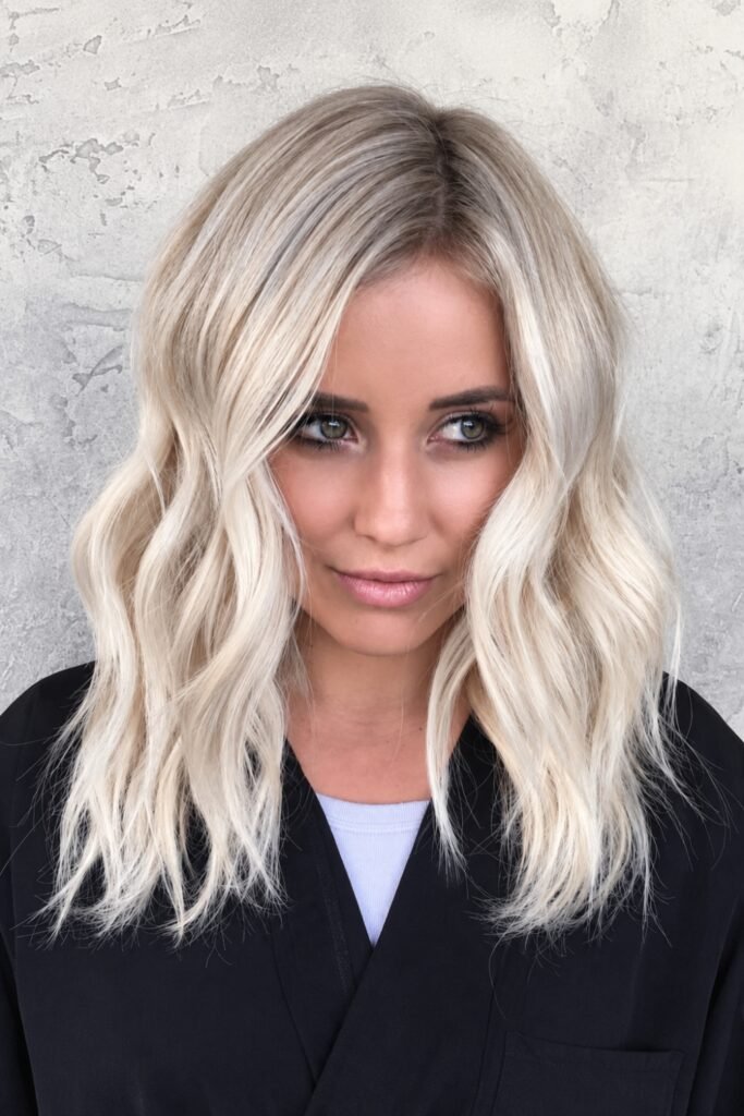 Wavy cool blonde lob with a darker root melt