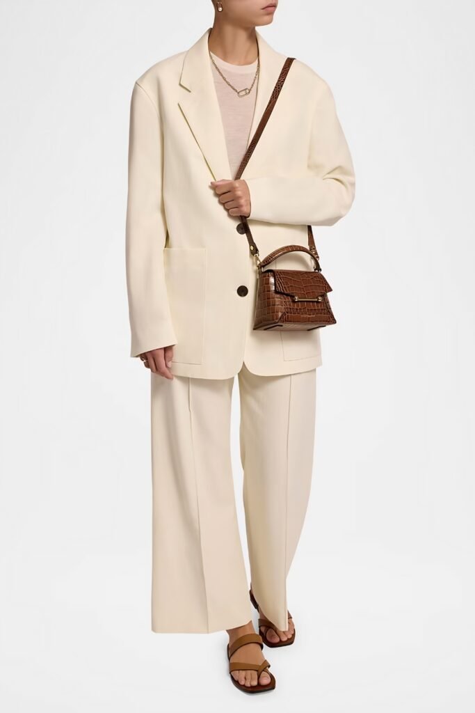 Woman in a cream suit with a brown croc-embossed bag