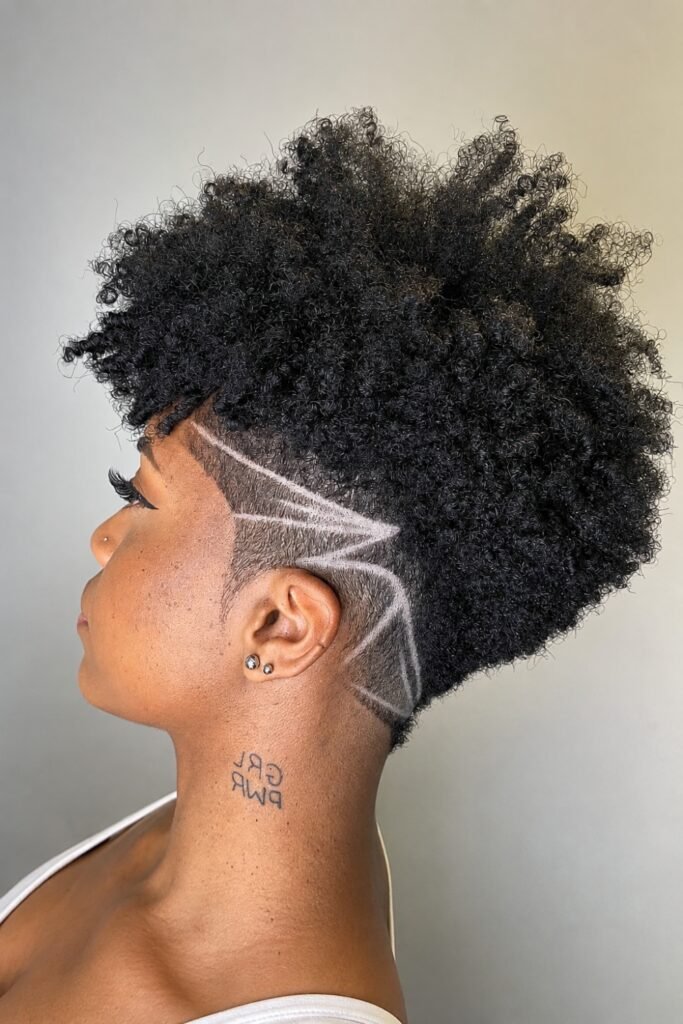Side view of a curly frohawk with tapered sides and shaved line details