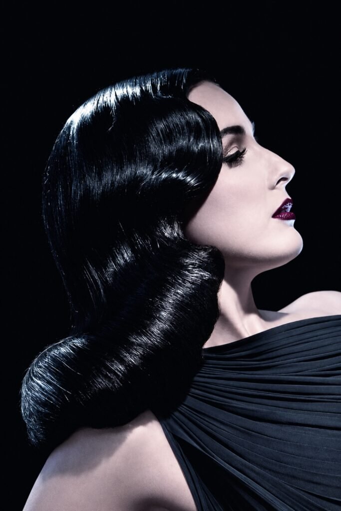 Side profile of glossy black hair set in sculpted Old Hollywood waves