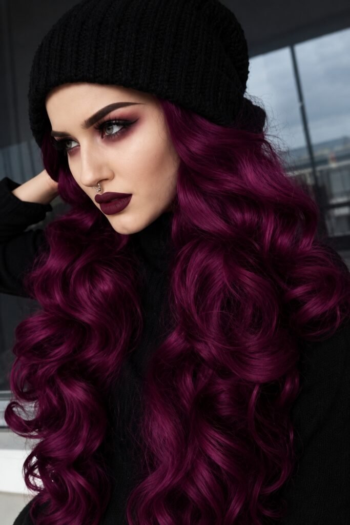 Deep plum curls worn under a black beanie