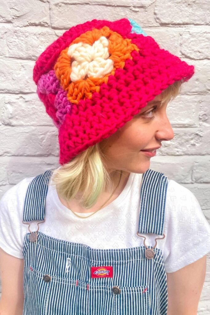 Woman in a pink granny-square crochet hat with denim overalls