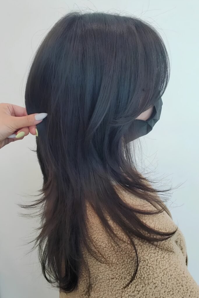 Back view of a grown-out layered cut with feathered ends