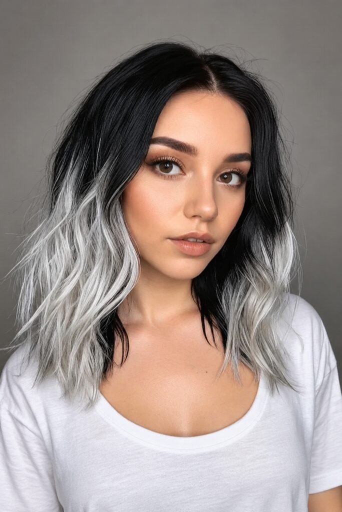 Shoulder-length wavy hair with black roots fading to silver ends
