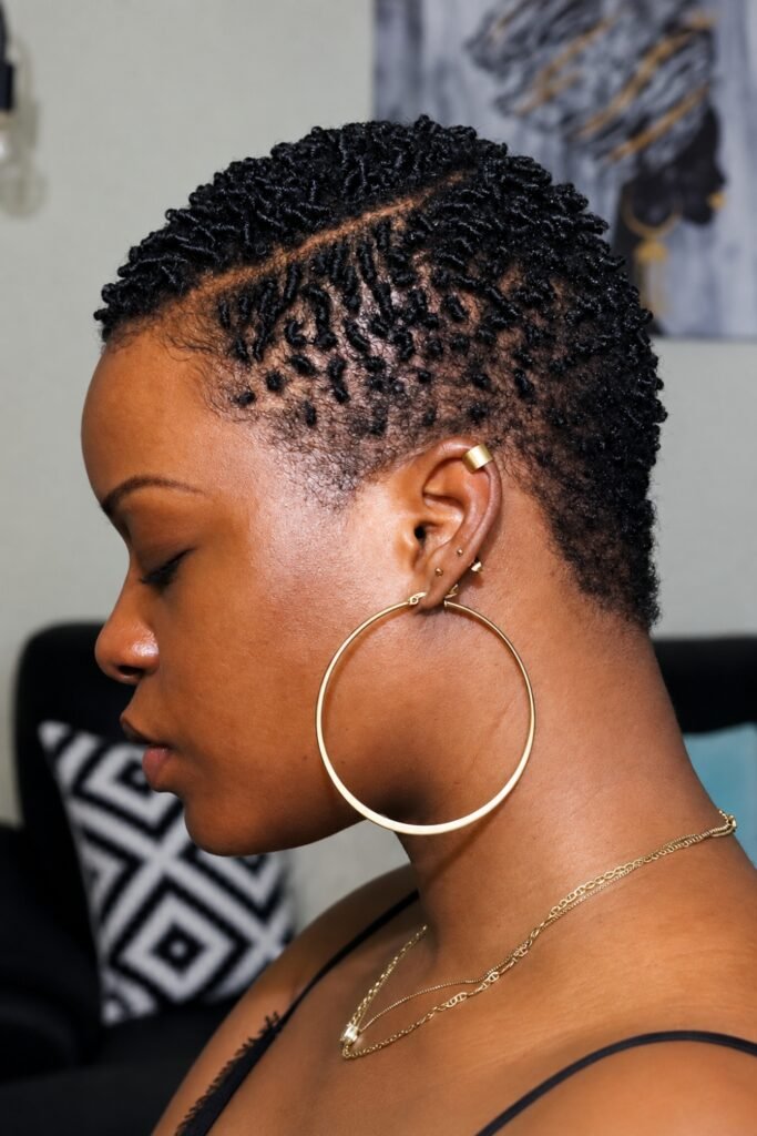 Side view of a natural coily taper with a shaved part and hoop earrings