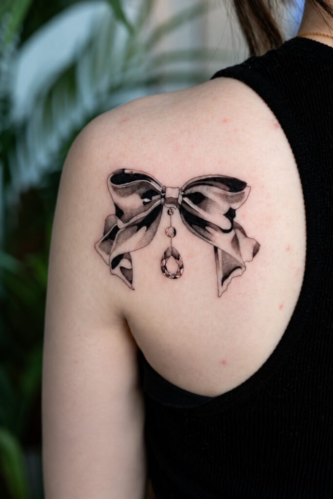 Ornamental bow with hanging jewel tattoo