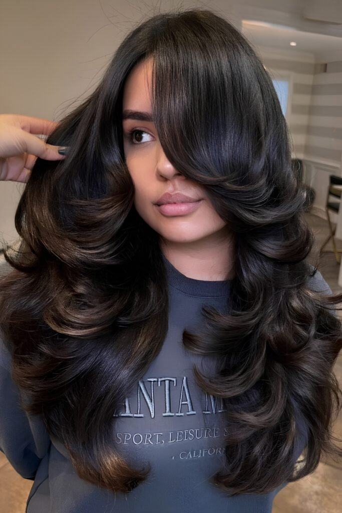 Glossy black wavy hair with a side part and butterfly layers