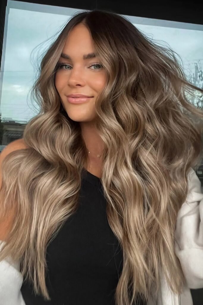 Wavy bronde hair with dark roots melting into milk tea lengths