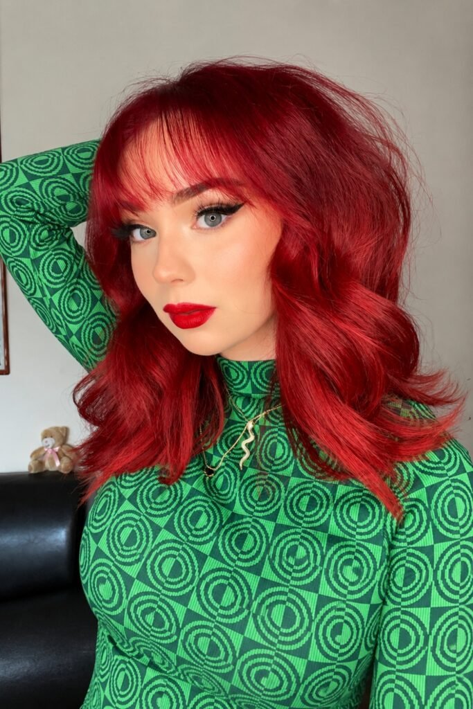Bright red wavy shoulder-length hair worn with a green patterned top