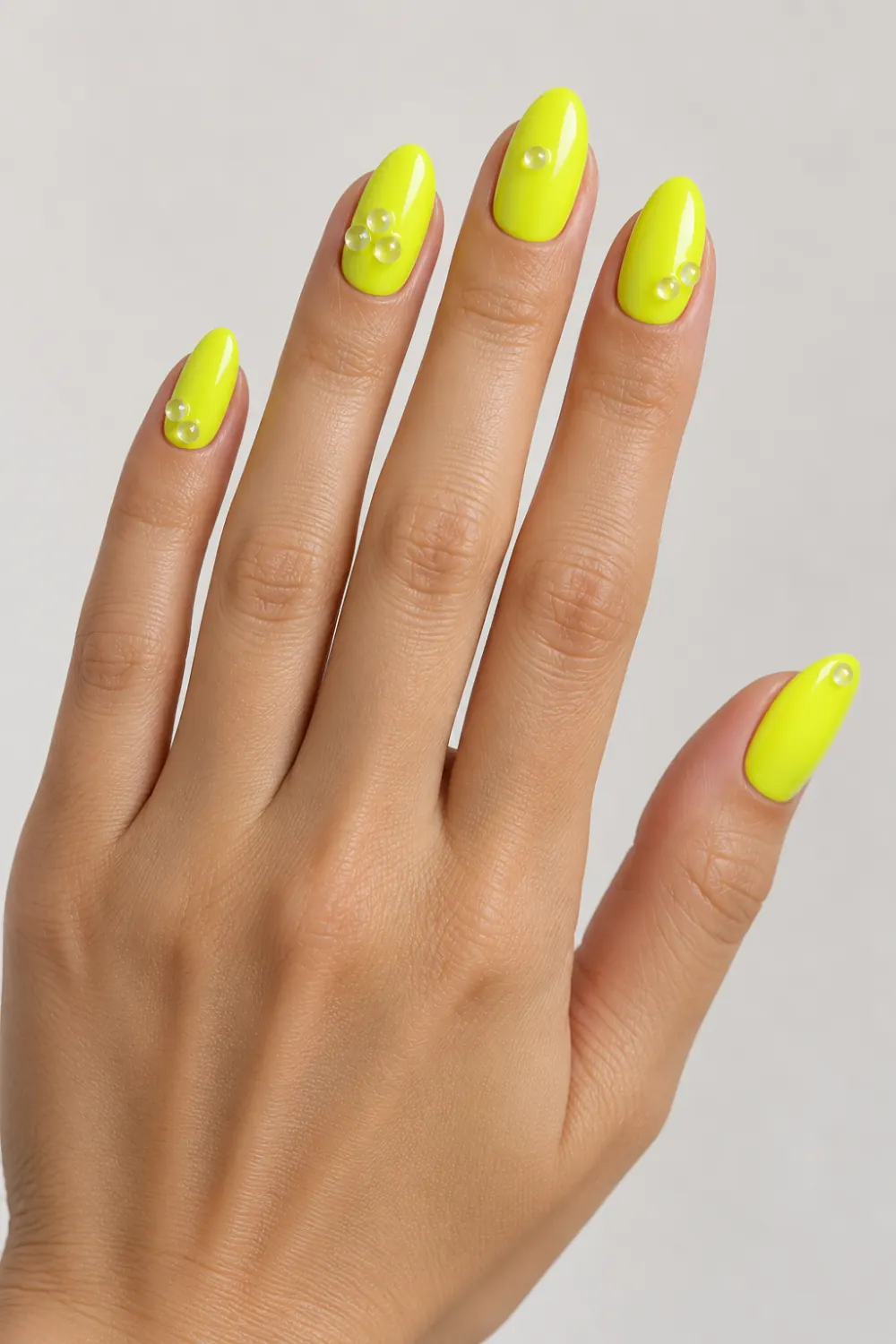 Neon yellow nails with small clear bead accents