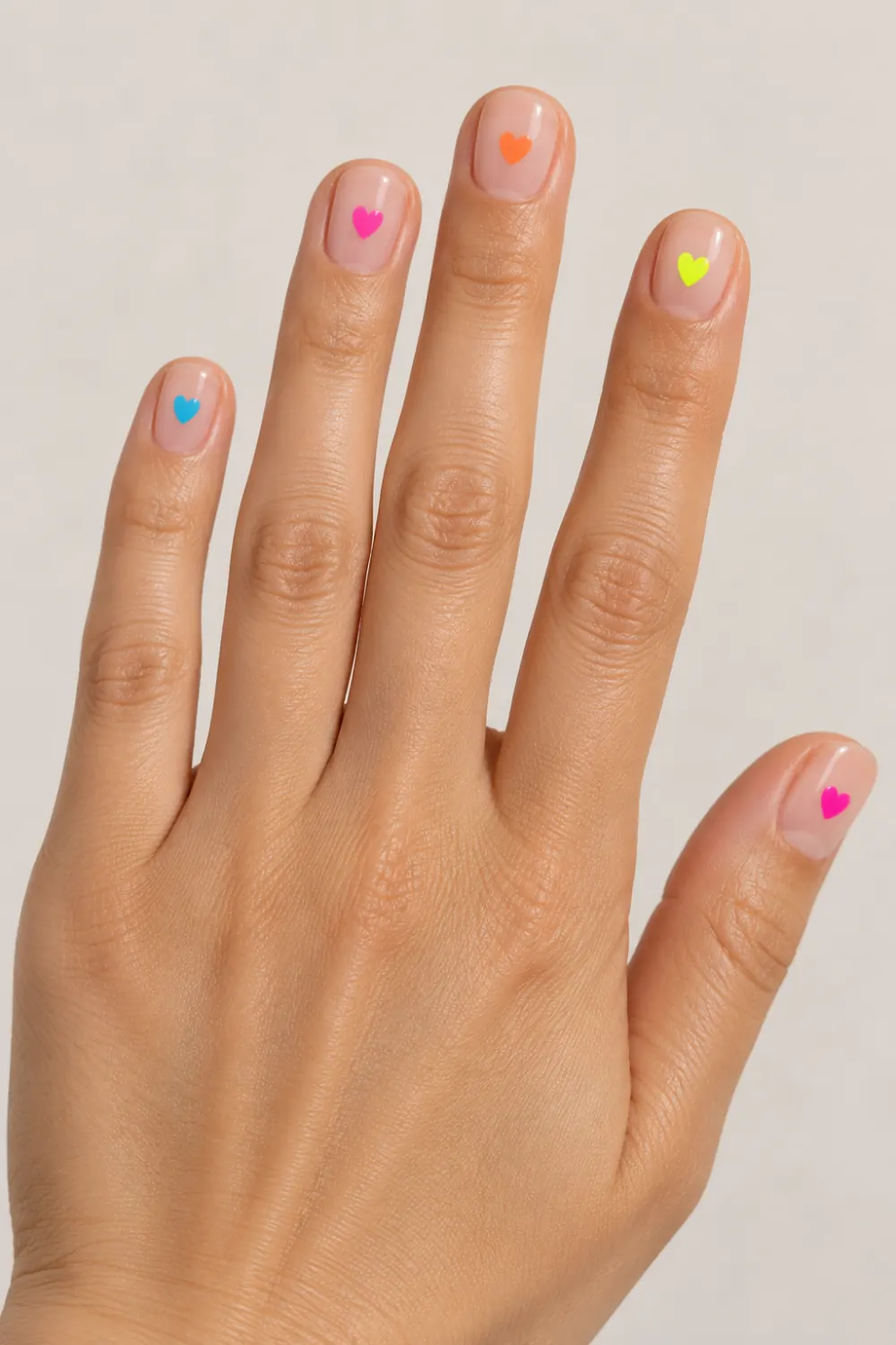 Nude manicure with a tiny neon heart on each nail
