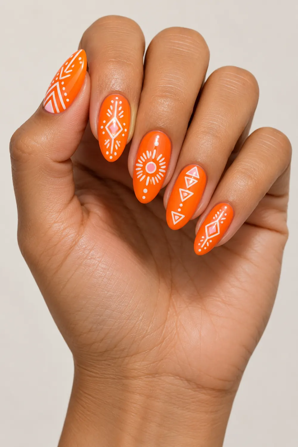 Neon orange nails with white tribal patterns and pink accents